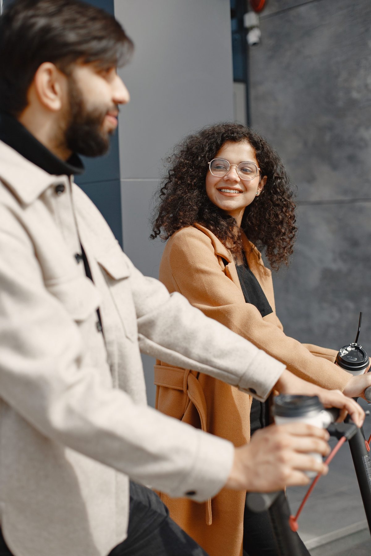 Two people with coffee beside an e-scooter in the city